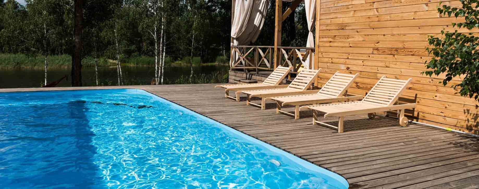 empty cozy chaise lounges near swimming pool at sunny day